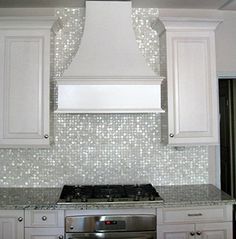 a stove top oven sitting inside of a kitchen next to white cupboards and drawers