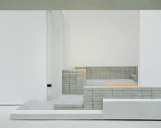 an empty room with white walls and flooring in the center, surrounded by concrete blocks