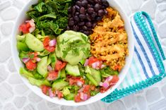 a white bowl filled with lots of different types of food next to a blue and white towel