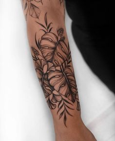 a woman's arm with flowers and leaves on it