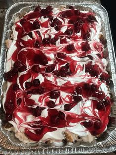 a cake with cherries and white frosting on it in a metal pan sitting on top of a table