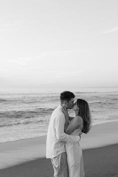 a man and woman kissing on the beach