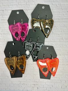 The unique pair of Ouija planchette earrings are crafted by hand, making each set a one-of-a-kind. The inking of each earring is done in a contrasting color to add a vibrant pop of style. Despite their large size, each earring is incredibly lightweight, and is designed to hang from a lever back for a secure and comfortable fit - even for those with stretched ears!Measurements~ 3 inches long~2 inches wide at widest point Ouija Planchette, Earring Organizer, Hand Making, Stretched Ears, Gold Flakes, Mozambique, Contrasting Colors, Large Size, Pink