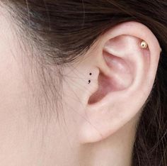 a woman's left ear has a tiny star tattoo on it