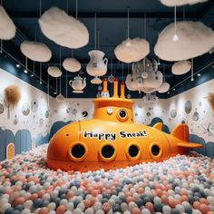 a yellow submarine floating on top of a pile of balls in a room filled with balloons