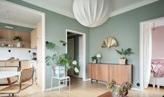 a living room filled with furniture next to a kitchen and dining room table covered in potted plants