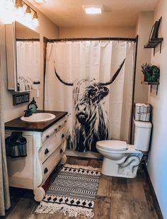 a bathroom with a shower curtain and rugs on the floor next to it is decorated with an image of a horned animal