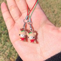 two small teddy bears are attached to tiny keychains on a person's hand