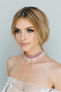 a woman with blonde hair wearing a choker and eye makeup looks at the camera