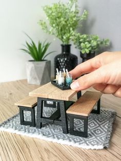 a hand is holding a miniature table and bench