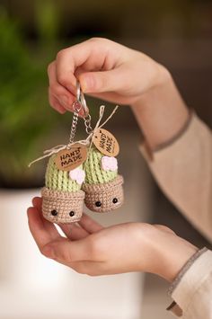 a person holding two tiny crocheted shoes with tags on the top of them