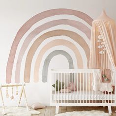 a white crib in front of a rainbow wall mural