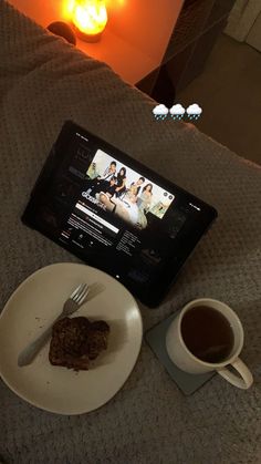 a table with a plate of food and a cup of coffee on it next to a tablet