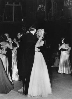 an old black and white photo of two people in formal wear dancing at a party