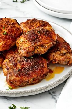 several pieces of chicken on a plate with sauce and parsley sprinkled around it