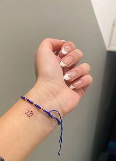 a woman's wrist with a blue beaded bracelet and the letter x on it