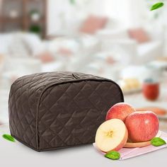 two apples and one piece of chocolate are on the table next to a brown bag