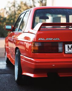 a red car parked in a parking lot next to another car with the word albina on it