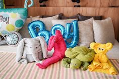 three stuffed animals sitting on top of a bed next to an air - filled balloon