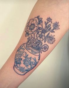 a woman's arm with flowers in a vase tattoo on it