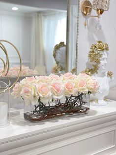 a vase filled with flowers sitting on top of a white dresser next to a mirror