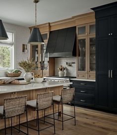 a kitchen with black cabinets and white counter tops, wooden flooring and two pendant lights hanging from the ceiling