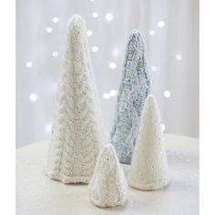 three knitted christmas trees sitting on top of a white table next to each other