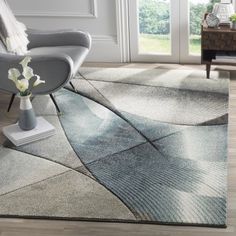 a living room area with a chair and rug on the floor, white flowers in a vase