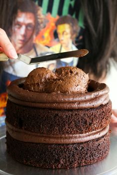 a person cutting into a chocolate cake on top of a metal platter with a knife