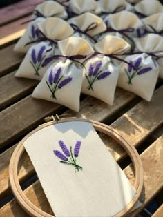 some purple flowers are sitting on a table next to a cross stitch pattern and a wooden hoop