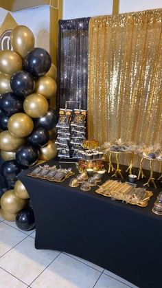 a table topped with black and gold balloons