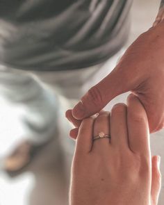 two people holding hands and touching each other's fingers, with one person wearing a ring on their finger