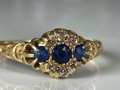 a gold ring with two blue stones on it's center and an oval shaped diamond in the middle