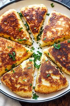 several pieces of grilled cheese on a white plate with parsley sprinkled