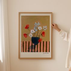 a woman standing next to a painting on the wall