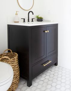 a bathroom with a sink, mirror and wicker basket on the floor in front of it