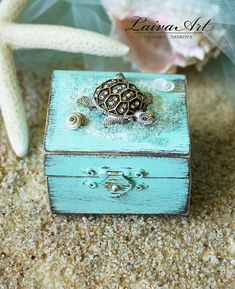 a small turtle sitting on top of a blue box next to a starfish shell