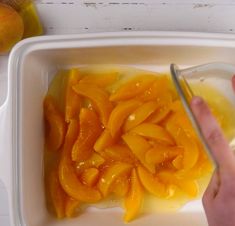 someone is cutting up some fruit in a container