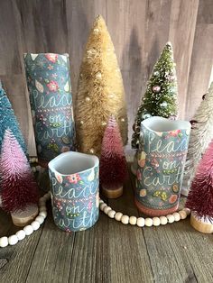 there are many different colored trees in the vases on the table with beaded balls around them