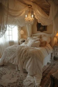 a white bed sitting under a chandelier in a bedroom next to a window