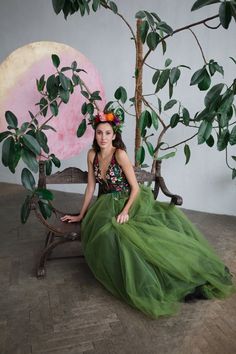 a woman in a green dress sitting on a bench next to a potted plant