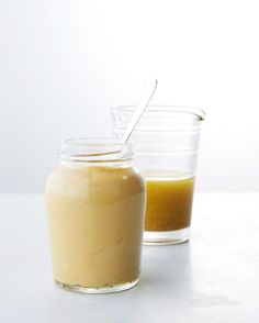 two jars filled with food sitting on top of a table next to each other and one has a spoon in it