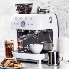 an espresso machine sitting on top of a counter next to some desserts