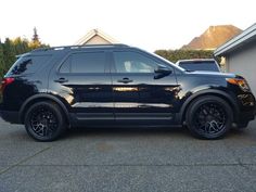 a black suv parked in a driveway next to a house