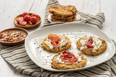 some food is on a white plate and next to two bowls with tomatoes, crackers and other foods