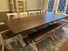 a dining room table with two benches in front of it and an area rug on the floor