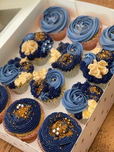 a box filled with blue frosted cupcakes on top of a wooden table