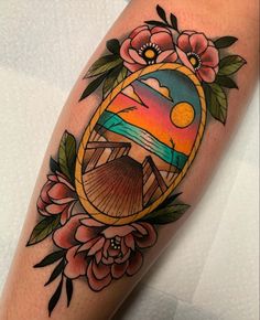 a colorful tattoo with flowers and a mirror on the arm that has an image of a sunset