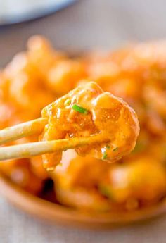 chopsticks holding up some food in a bowl