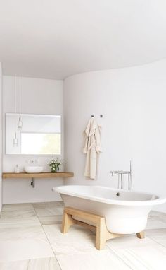 a white bath tub sitting next to a wooden shelf